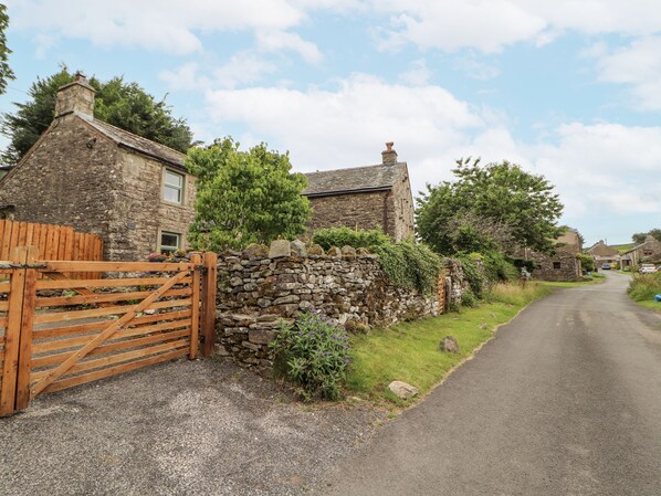 A stone house with a wooden gate, a stone wall, and a narrow road. - White House (Penrith)