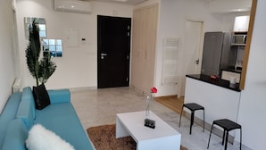 Un salon moderne avec un canapé bleu, une table basse blanche et un petit tapis.