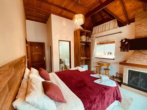 A bedroom with a large bed, wooden ceiling, a fireplace, and a wooden wardrobe. - Davilas Inn (Camanducaia)