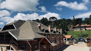 A traditional chalet-style building with a sloped roof, multiple chimneys, and a staircase leading to an upper level. - Davilas Inn (Camanducaia)