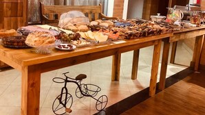 A buffet table with various food items, a bicycle decoration, and a brick wall in the background. - Davilas Inn (Camanducaia)
