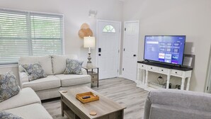 Ein Wohnzimmer mit einer Couch, einem Couchtisch, einem Fernseher und einem kleinen Schrank.