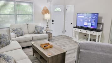 Ein Wohnzimmer mit einer Couch, einem Couchtisch, einem Fernseher und einem kleinen Schrank.