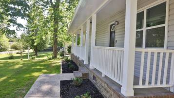 A house with a covered porch, a brick foundation, and a well-maintained lawn.