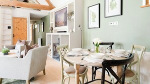 A dining area with a round table set for four, surrounded by chairs. There is a wooden ceiling structure above, and a fireplace is visible in the background. - 2 bedroom accommodation in Bramley, near Tadley (Bramley, near Tadley)