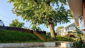 Ein Wohngebiet mit einem großen Baum, einer Treppe und einem Haus mit einer Veranda.