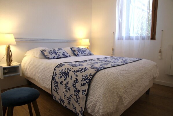 A neatly made bed with a white and blue floral bedspread, two matching pillows, and two bedside lamps on wooden nightstands.