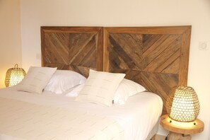 Una cama con cabecera de madera, ropa de cama blanca y dos lámparas de noche.