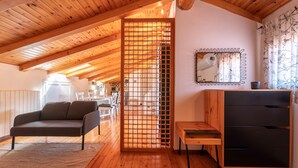 Um quarto aconchegante com teto de madeira, um sofá, uma mesa pequena, um armário e um biombô decorativo.
