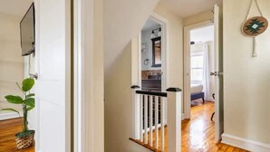 A hallway with wooden flooring, white walls, and a staircase with a white railing. - FIFA 2026 HQ: Family Affair in Philly Suburbs - Free Parking (Clifton Heights)