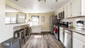 A modern kitchen with white cabinets, stainless steel appliances, and a wooden floor. - FIFA 2026 HQ: Family Affair in Philly Suburbs - Free Parking (Clifton Heights)
