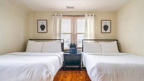 A room with two beds, a small table, and a window with curtains. - FIFA 2026 HQ: Family Affair in Philly Suburbs - Free Parking (Clifton Heights)
