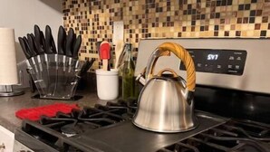 Une cuisine équipée d’une cuisinière à gaz, d’une bouilloire et d’un ensemble de couteaux.