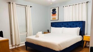 Une chambre d’hôtel avec un grand lit, un plancher en bois, une table de chevet et une fenêtre avec des rideaux.