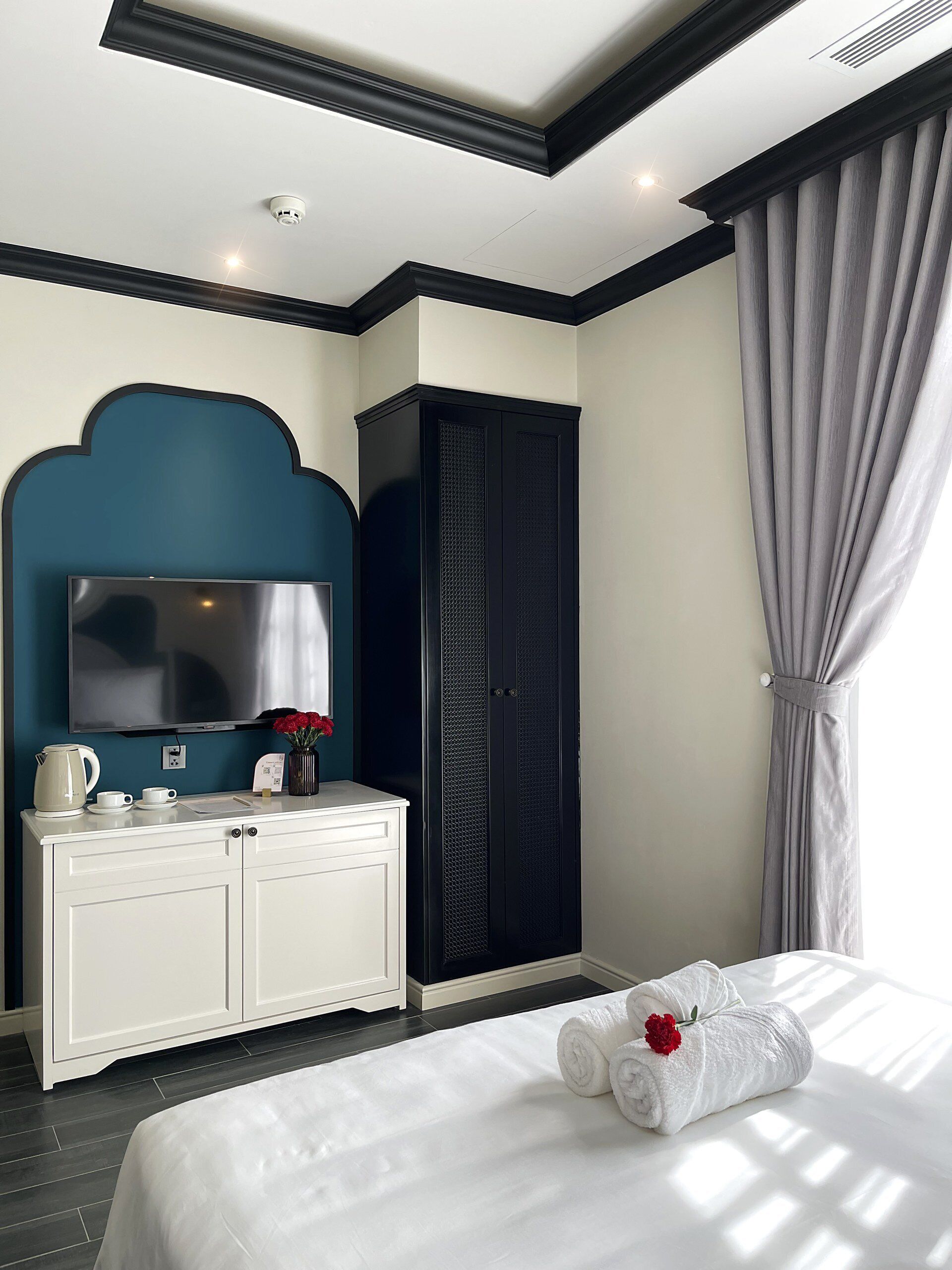 A hotel room with a bed, a TV, a cabinet, and a window with curtains.