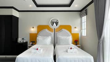 Hotelkamer met twee bedden, een ronde spiegel erboven, een tafeltje met waterkoker en kopjes, en een raam met gordijnen.