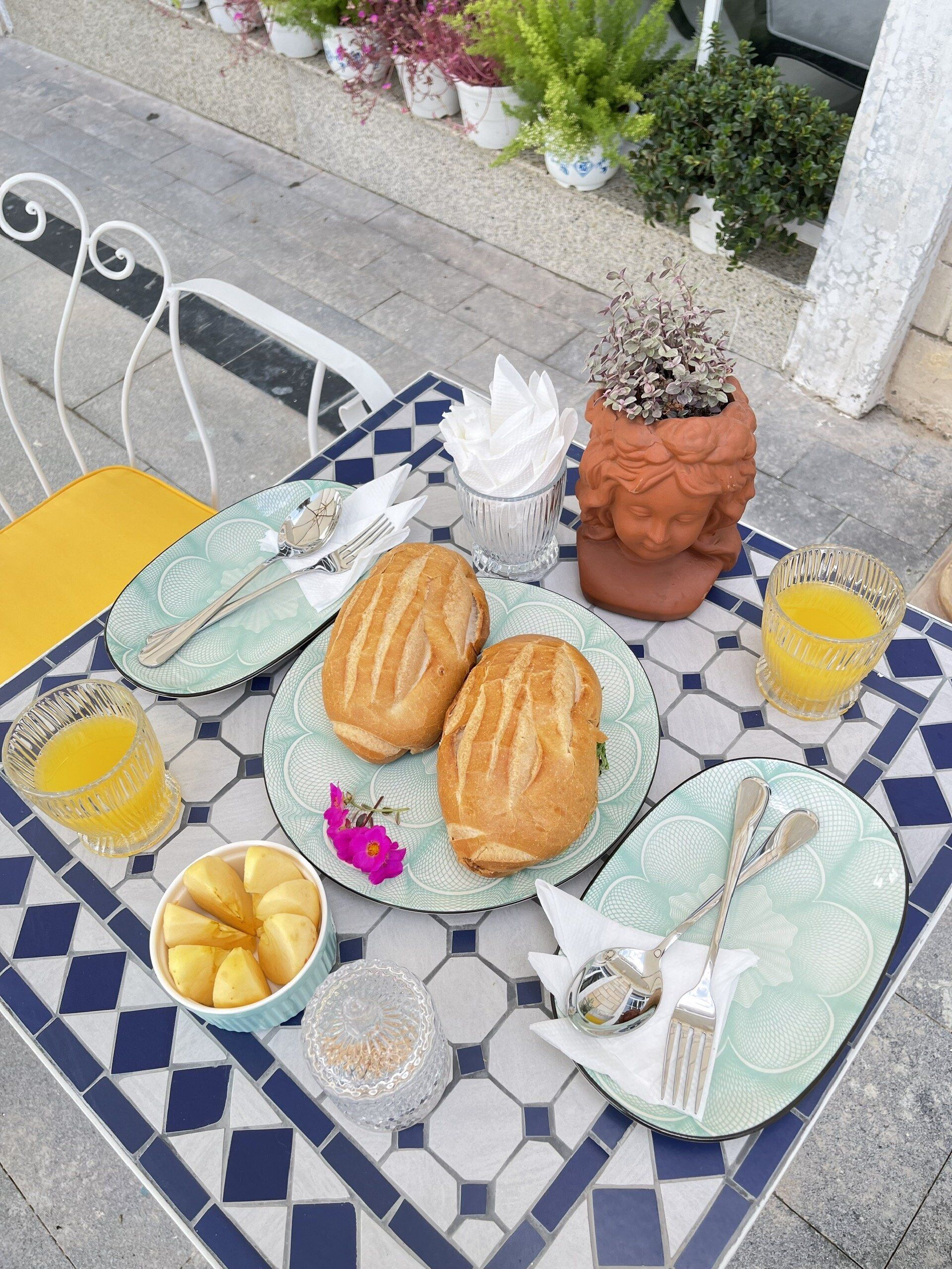 Een gedekte tafel met brood, fruit en een glas sinaasappelsap.