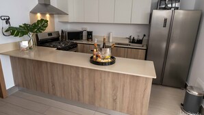 A modern kitchen with a central island, stainless steel appliances, and wooden cabinetry. - Luxurious Chic Penthouse Navio Beach (Punta Cana)