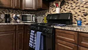 A kitchen with wooden cabinets, a microwave, a stove, and a tiled backsplash.