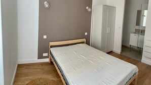 A bedroom with a wooden bed, a wardrobe, and a bathroom visible through an open door.