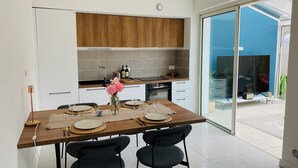A modern kitchen with wooden cabinets, a dining table set for two, and a large sliding glass door leading to an outdoor area.
