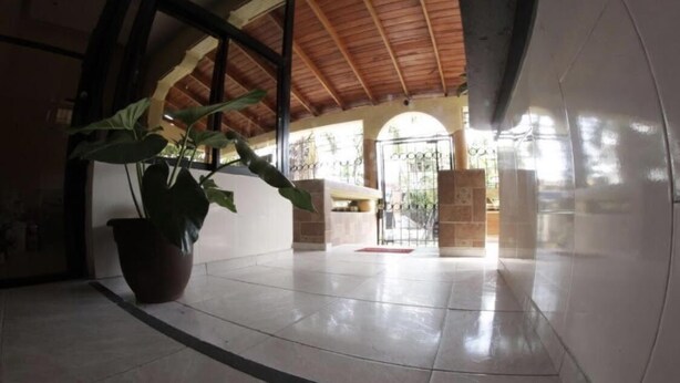 A spacious hallway with a tiled floor, a large potted plant, and a wooden ceiling. - Caribbean Hotel Santo Domingo (Santo Domingo)
