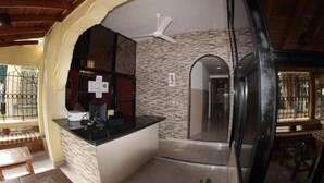 A reception area with a counter, a ceiling fan, and a stone wall. - Caribbean Hotel Santo Domingo (Santo Domingo)