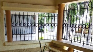 A covered outdoor seating area with a bench and a table, surrounded by a metal fence. - Caribbean Hotel Santo Domingo (Santo Domingo)