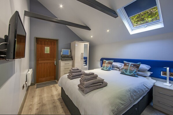 A modern bedroom with a bed, a wardrobe, a desk, and a window with a view of greenery. - Luxury Self Catering Lodge with Hot Tub - Palms 2, Loch Etive, North Connel (North Connel)
