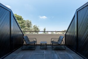 A balcony with two chairs and a small table, overlooking a cityscape. - Domus Carmel Hotel (Haifa)