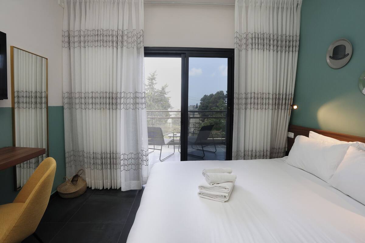 Une chambre d’hôtel avec un lit, un bureau, une chaise et une vue sur le balcon extérieur.