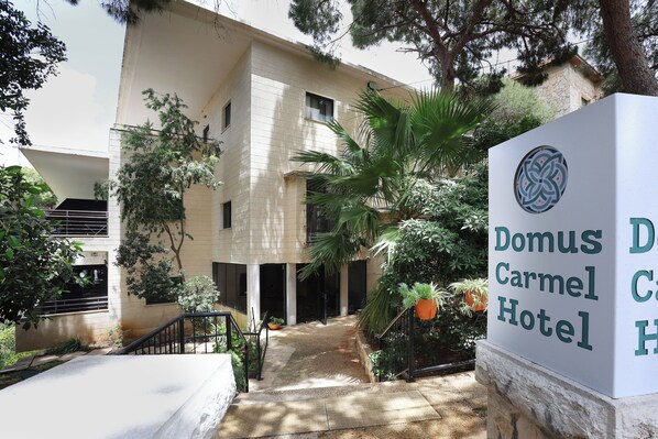 A building with a sign for Domus Carmel Hotel. - Domus Carmel Hotel (Haifa)