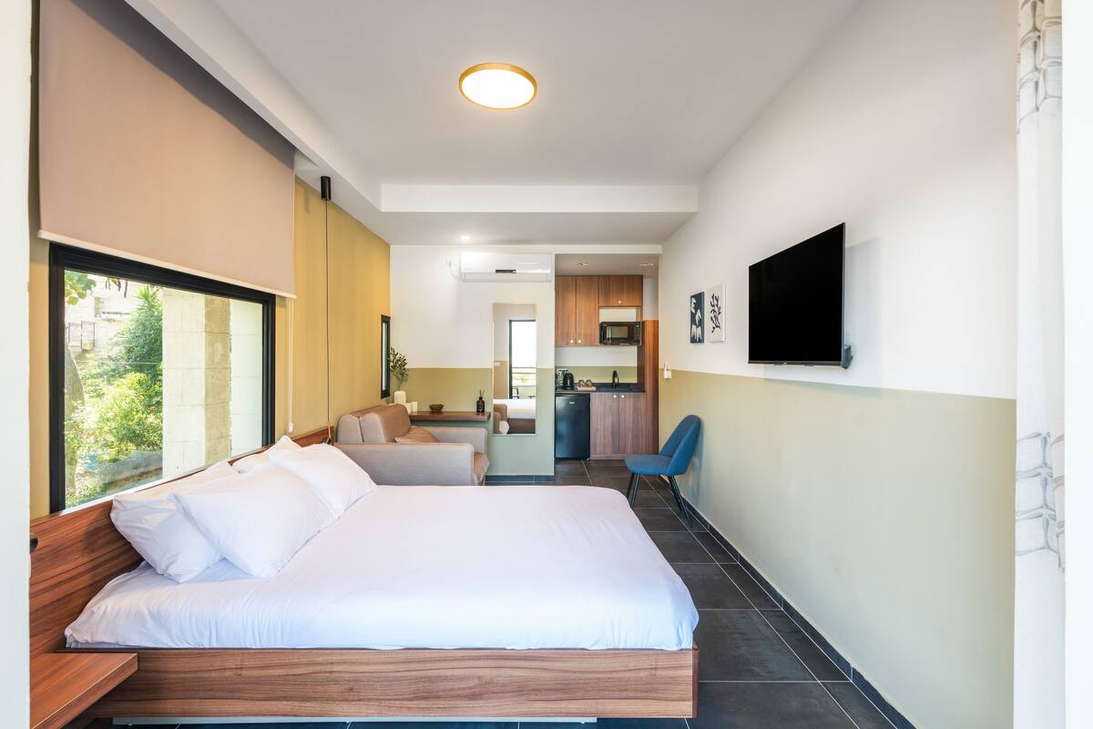 Une chambre d’hôtel moderne, dotée d’un grand lit, d’un bureau, d’une chaise et d’un téléviseur fixé au mur.