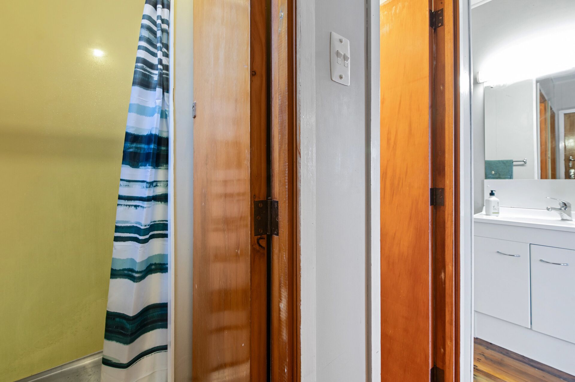 A bathroom with a white sink, a mirror, and a striped shower curtain.