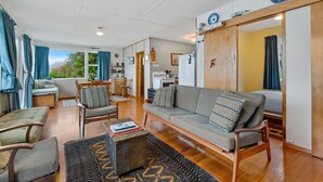 Een ruime woonkamer met een bank, stoelen, een salontafel en uitzicht op de omgeving.