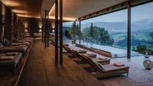 A spa area with massage chairs, a reception desk, and a view of the countryside. - Bergkristall - Mein Resort im Allgäu (Oberstaufen)