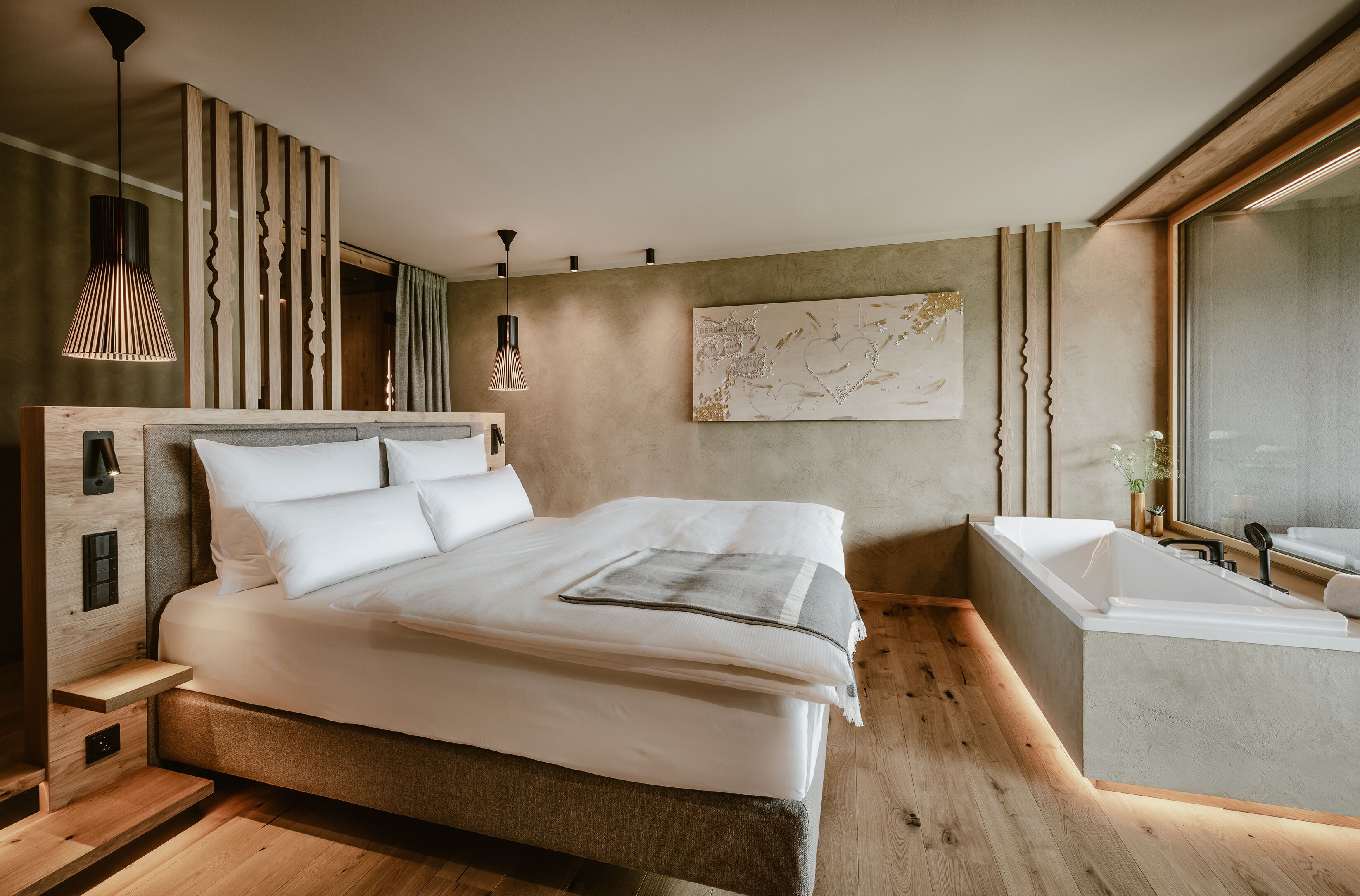 Une chambre moderne avec un grand lit, une baignoire intégrée et un plancher en bois.