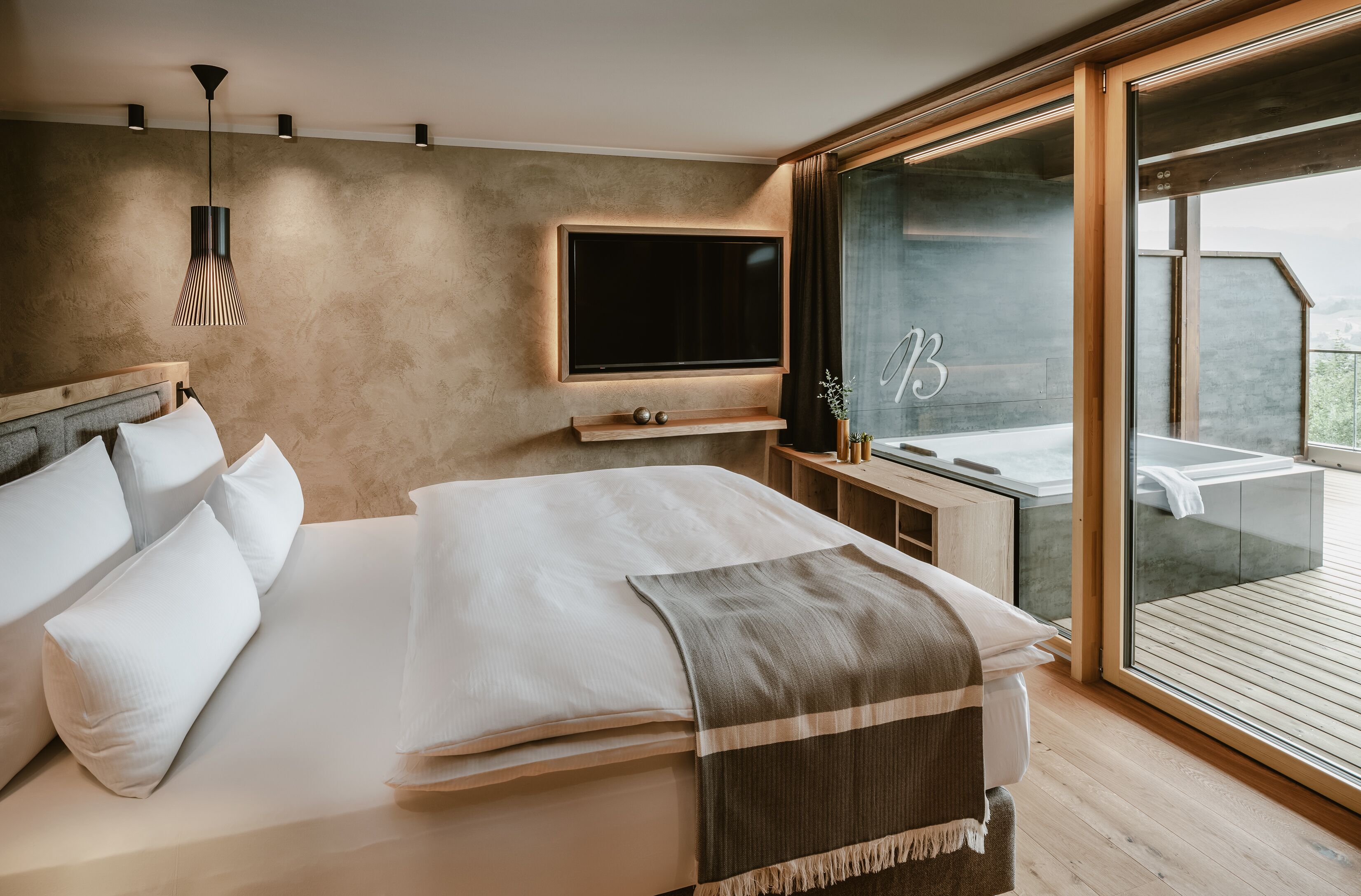 Una camera da letto moderna con un letto grande, una TV a parete e un balcone con porta in vetro.