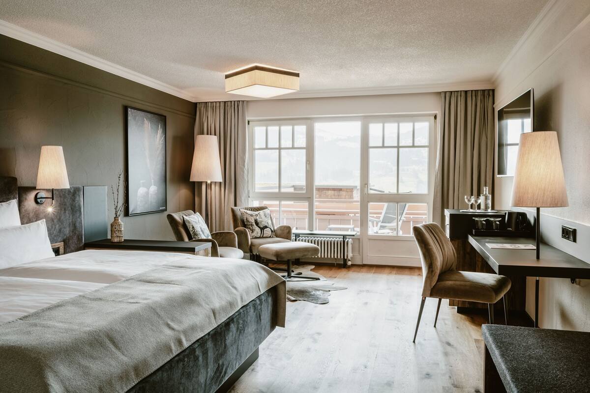 Habitació d'hotel amb un llit gran, un escriptori, una cadira i vista a la ciutat.