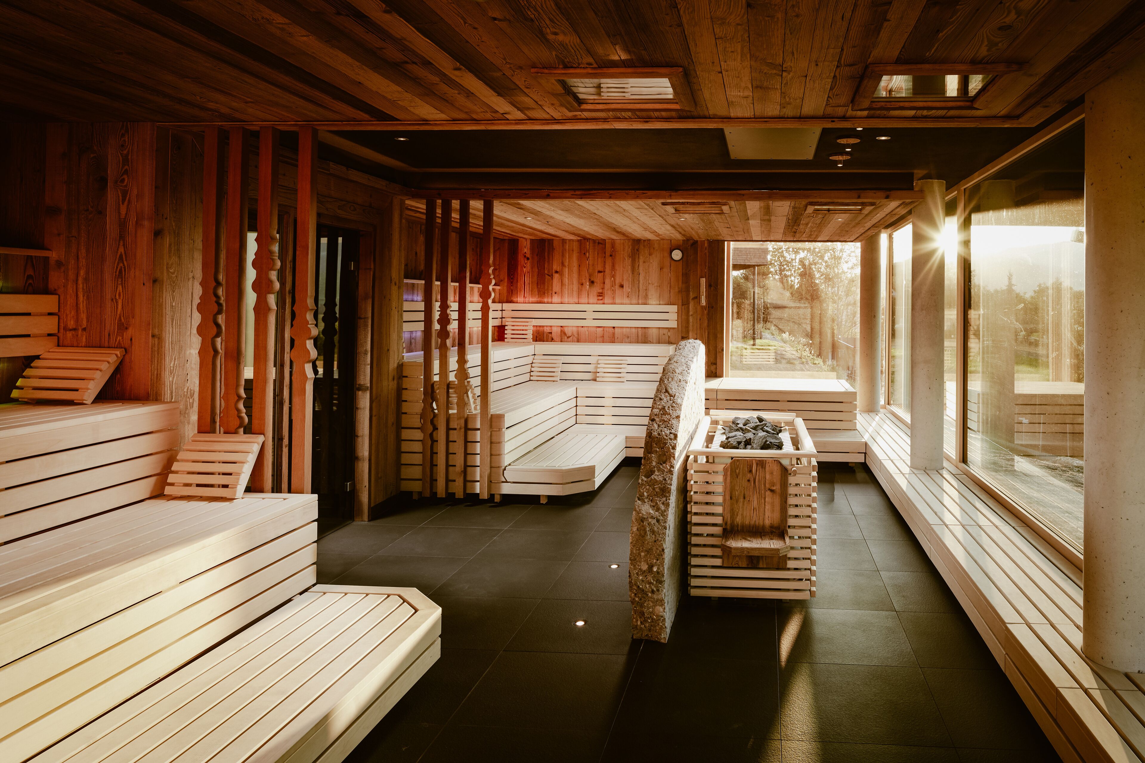 Un sauna avec des bancs en bois et un banc sur lequel se trouve un bain en pierre.