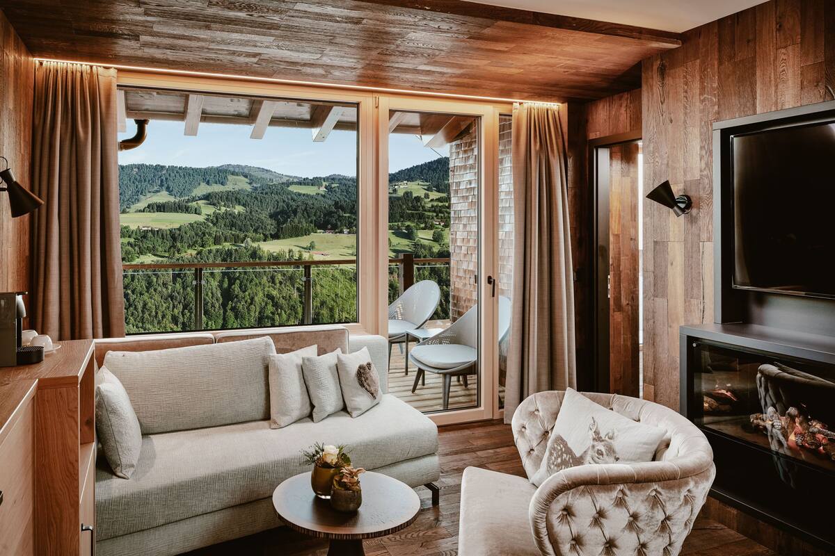 Un saló acollidor amb un sofà, una butaca i una televisió plana. Una finestra gran ofereix una vista panoràmica del camp.
