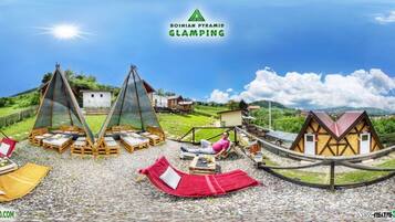 Un lugar para glamping con estructuras de madera, hamacas y una vista despejada del paisaje circundante.