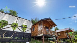 A wooden cabin with a balcony, surrounded by a wooden fence and a white curtain.