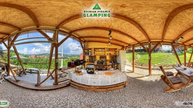 A circular wooden structure with a thatched roof, a central table, and seating areas.