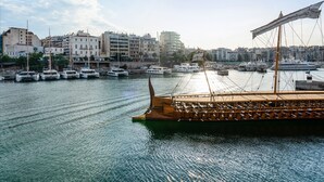 Ein Hafen mit mehreren vertäuten Booten, ein Holzboot im Vordergrund und Gebäude im Hintergrund.