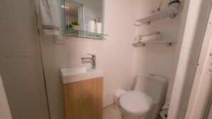 A bathroom with a white sink, wooden cabinet, white toilet, and glass shelves with toiletries. - ★Best Location in Bogotá. Private Studio+WIFI ★ (Bogotá)