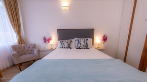 A neatly arranged hotel room with a large bed, a chair, two bedside tables with lamps, and a window with curtains. - ★Best Location in Bogotá. Private Studio+WIFI ★ (Bogotá)