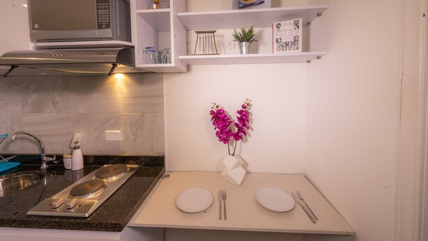A modern kitchen with a built-in microwave, a sink with a faucet, and a dining area with two white plates and cutlery. - ★Best Location in Bogotá. Private Studio+WIFI ★ (Bogotá)