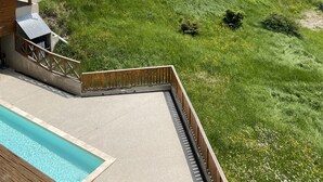 Un hotel con piscina, rodeado de exuberantes colinas verdes y un cielo despejado.