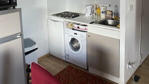 Cocina compacta con microondas, estufa y lavadora.